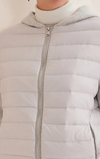Close-up of light gray hooded puffer jacket: quilted panels and zip front with zipper pull