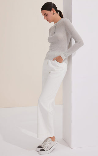 Light gray henley top with long sleeves and button placket over white pants