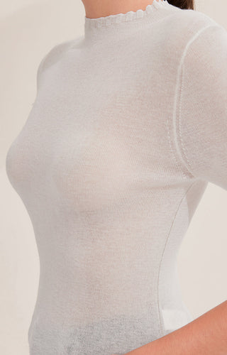 Close-up of white knit top neckline and upper back seam detail
