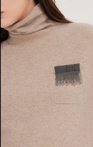 Close-up: camel short-sleeve turtleneck sweater pocket with silver bead fringe detail