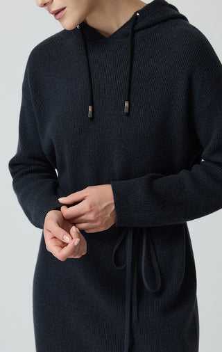 Black hooded knit dress close-up: drawstring hood and waist tie on wool fabric