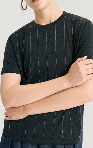 Close-up of dark knit top with vertical lurex thread stripes and ribbed hem