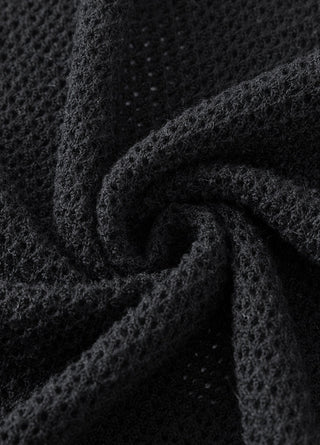 Black knit fabric close-up with textured open-weave stitch pattern