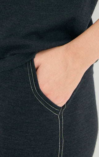 Close-up: dark pant front with beaded vertical trim along pocket/side seam