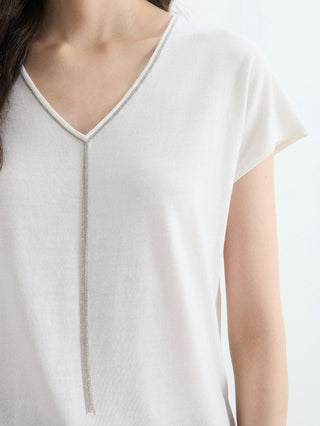 Close-up: white V-neck knit with silver bead trim along neckline and center