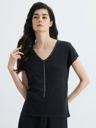 Close view of black V-neck knit top with silver bead trim and center drop detail
