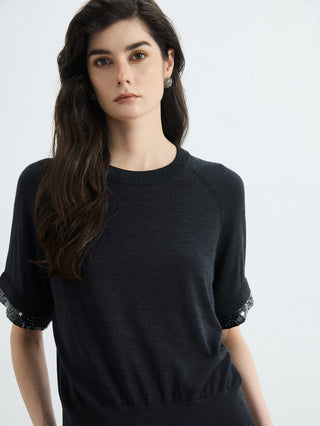 Black knit top with silver beaded cuffs on short sleeves, relaxed crew neckline