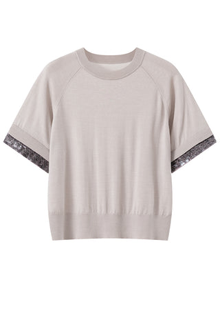 Beige knit top flat lay with silver beaded sleeve cuffs and crew neckline