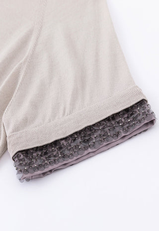 Beige sleeve cuff with silver-toned beaded trim along hem