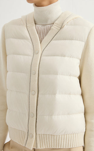 Cream hooded puffer jacket close-up with snap buttons and quilted horizontal panels