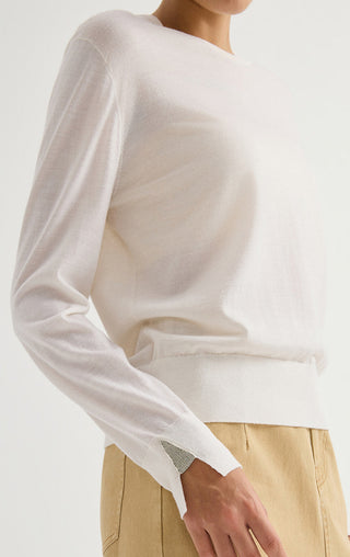 Women’s fine wool crewneck sweater in white, shown from the side with cuff detail.