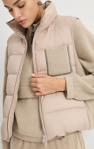 Camel puffer vest detail view with ribbed pocket trim, quilted front, and zip closure.