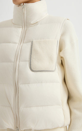 Ivory white puffer vest close-up with ribbed flap pocket and quilted insulated panels.