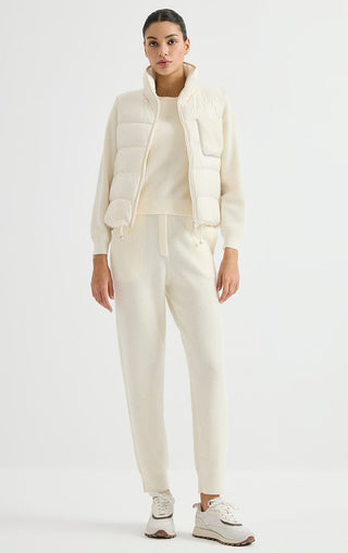 Ivory white cashmere puffer vest with full zipper and flap chest pocket, shown with joggers.