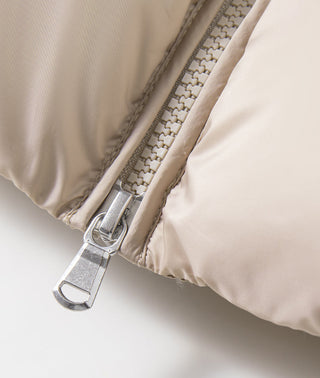 Beige puffer vest zipper close-up with metal pull and quilted shell