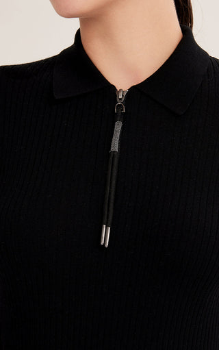 Close-up of black ribbed wool zip polo sweater collar and shimmer pull tab