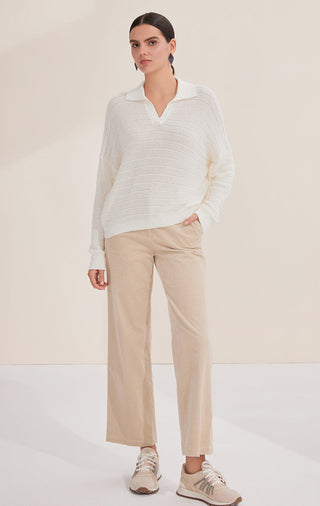 White textured knit pullover with V-neck and fine sequins; paired with light trousers
