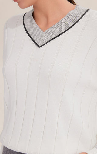 Close-up of white V-neck sweater collar with contrast trim and fine knit stripe pattern