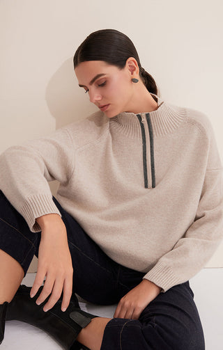 Camel half-zip wool sweater, seated pose, front view with dark striped zipper placket