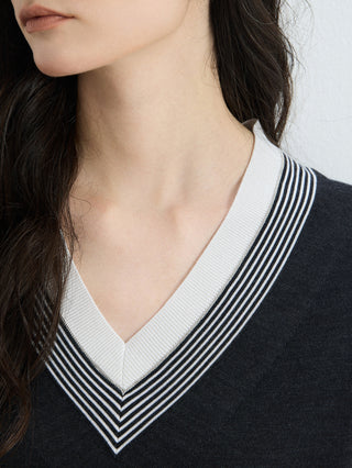 Close-up: graphite gray V-neck knit with white and striped contrast trim at collar