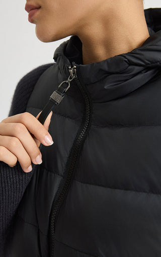 Black hooded puffer vest detail with metal zipper pull and quilted front panel