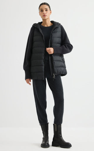 Black hooded puffer vest worn with ribbed knit sleeves and full-zip front