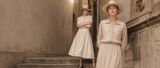 Neutral women’s summer outfits styled in a historic European stone alley with straw hats and soft natural light