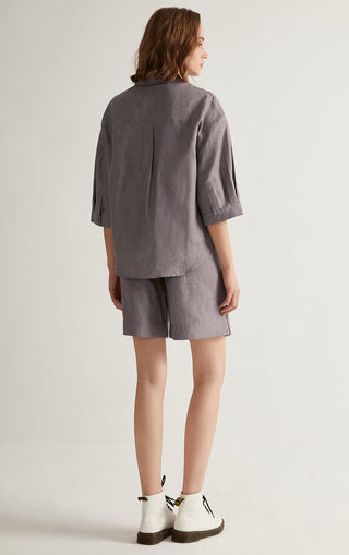 Back view of gray linen shorts with elastic waistband and full pleated shaping.