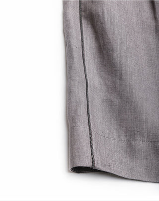 Bottom hem close-up of gray linen shorts with contrast-stitched side seam.