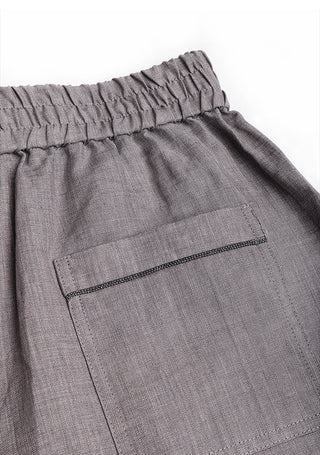Close-up of gray linen shorts front with pocket seam and elastic waistband.