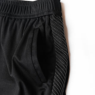 Close-up: black elastic waistband and beaded side panel with stitched stripe detail