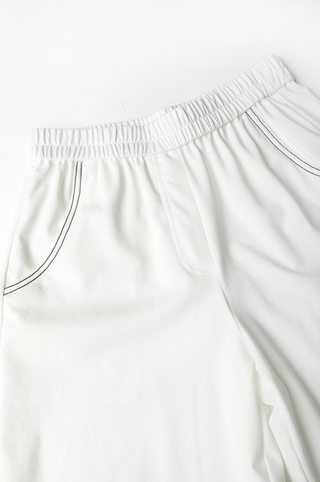 White shorts front waist view: gathered elastic band and black-trimmed drawcord