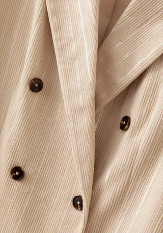 Beige pinstripe blazer lapel close-up with shiny sequin stripes and dark buttons