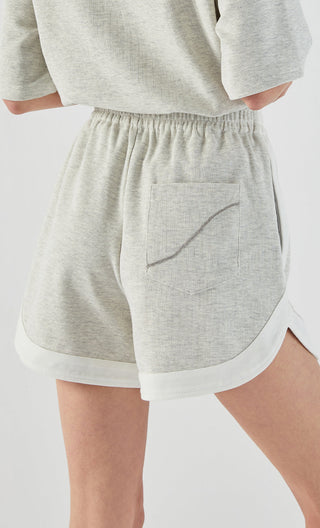 Light gray shorts back view with stitched pocket detail and white contrast trim