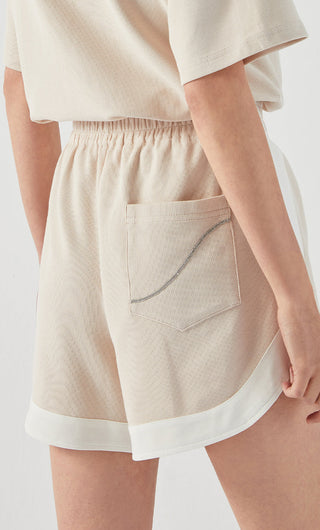 Apricot cotton shorts with front pocket, elastic waistband, and white contrast trim