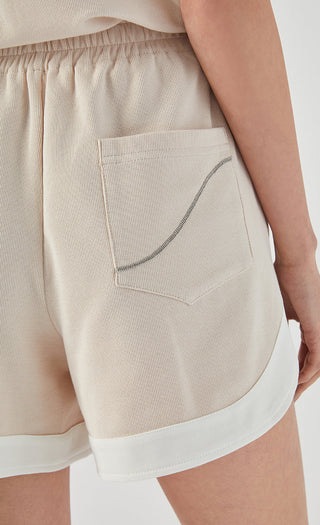 Apricot shorts with curved stitching on front pocket and white contrast trim
