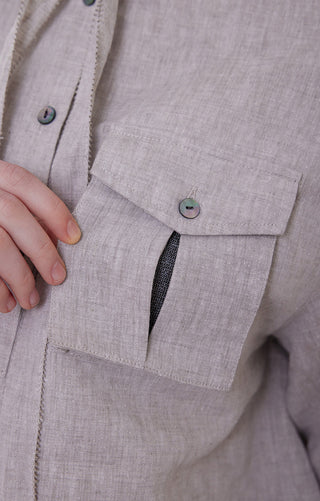 Light purple linen utility shirt pocket and button detail; hand holding collar area