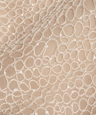 Close-up of apricot embroidered silk mesh pattern with small bead-like details