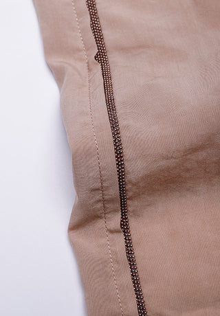 Close-up of rose shorts with dark beaded trim along the side seam
