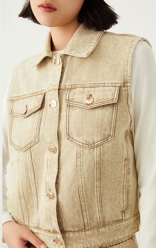 Light tan denim sleeveless jacket close-up with pointed collar and metal buttons