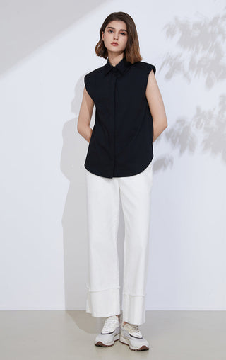 Black sleeveless button-up shirt with pointed collar, worn with white trousers