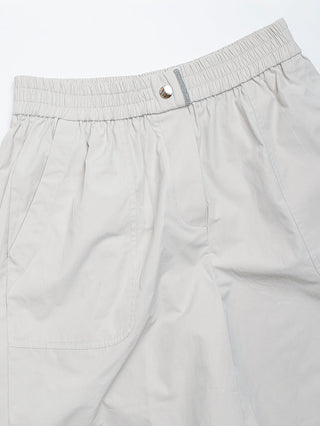 Light gray shorts close-up: gathered elastic waistband with emblem snap and front pockets