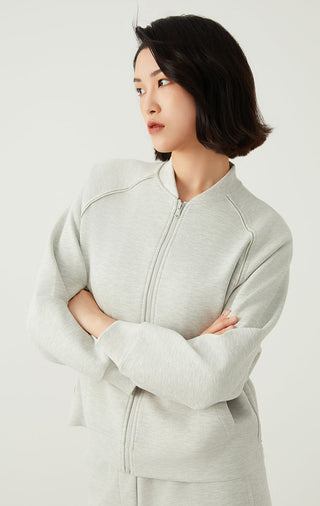 Light gray zip-up jacket with diagonal seam piping and long sleeves, front zipper.