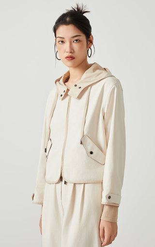 Beige hooded short jacket with snap buttons, drawstring hood, and chest pocket
