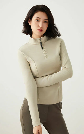 Sage green half-zip knit top with beaded zipper pull and high neck, folded arms