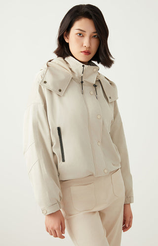 Light beige hooded puffer jacket with stand collar, snap buttons, and chest zipper