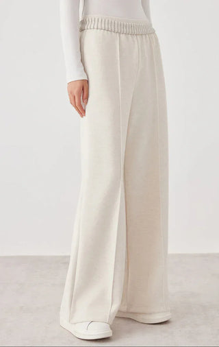 White wide-leg knit pants, side view; smooth knit with elastic waistband