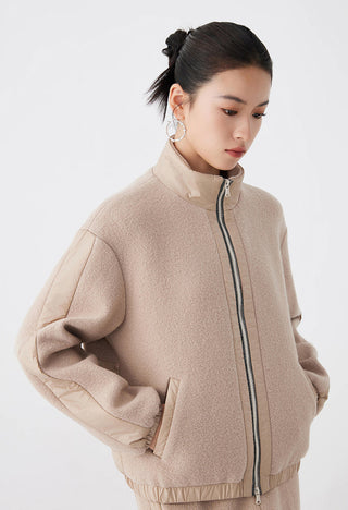 Camel jacket close view: stand collar, center zipper, and elastic cuff detail
