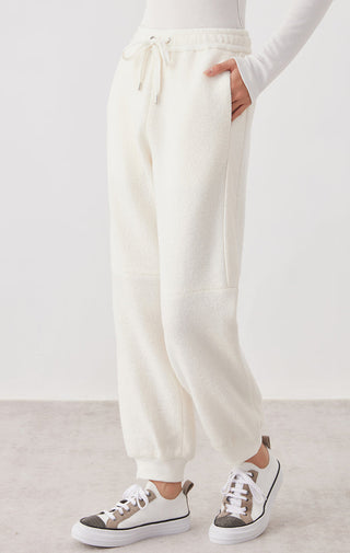 White knit jogger pants side view, elastic waist drawstring and cuffed ankle