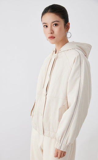 Light tan hooded quilted jacket, side view with snap front, hood drawcord, ribbed sleeve cuffs